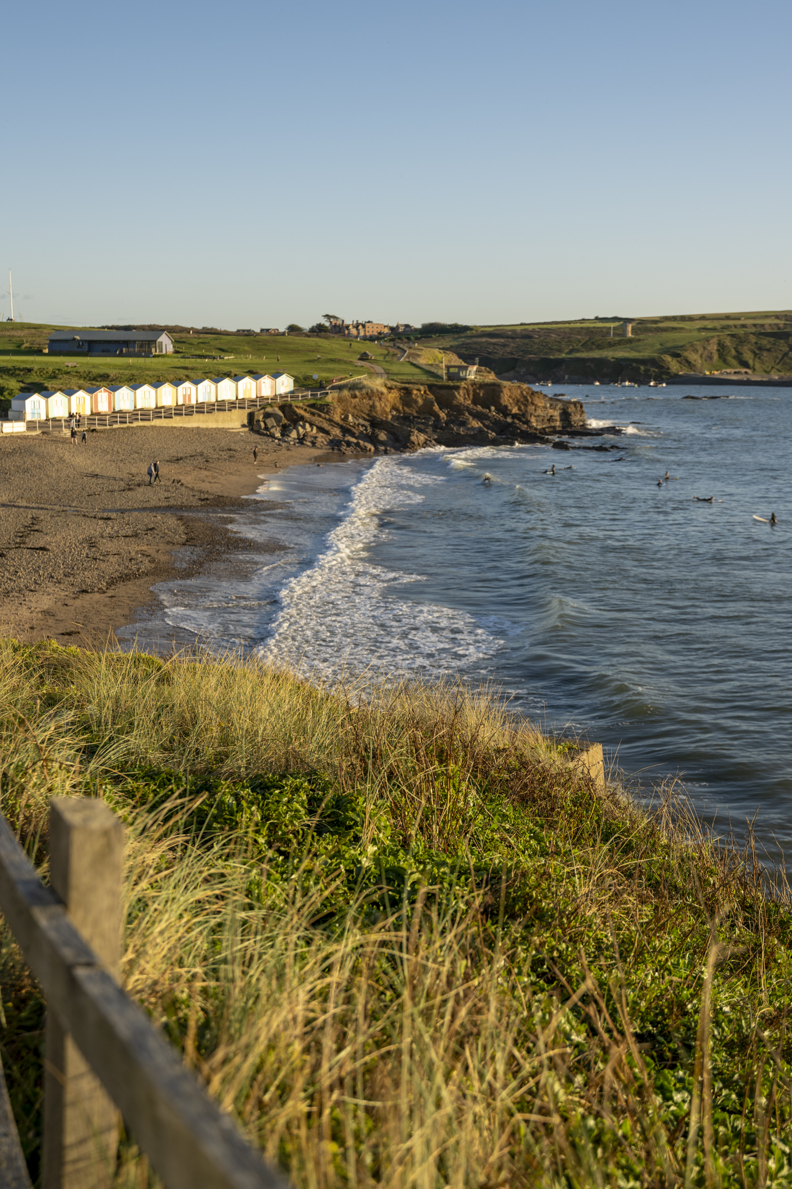 Beach huts and surfers on Crooklets beach